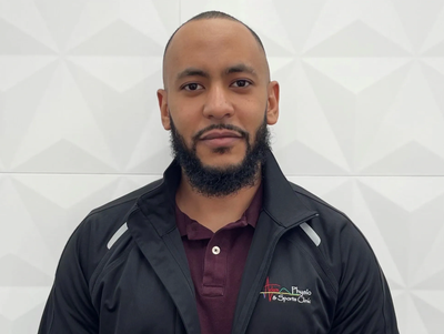 Man with a beard wearing a black jacket and maroon shirt.