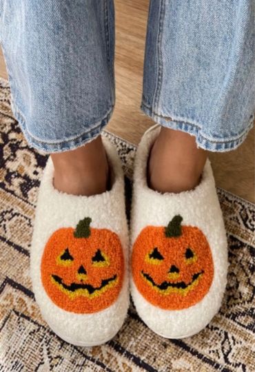 Cozy white slippers with cheerful pumpkin faces, perfect for fall.