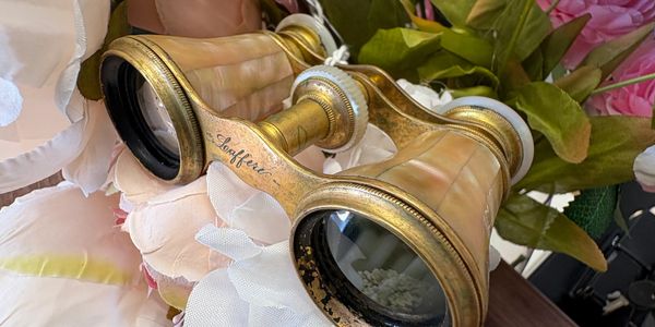 Antique gold opera glasses among flowers.