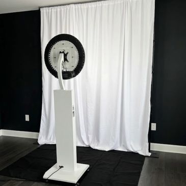 Standing photobooth with white, cloth backdrop.