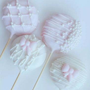 Pink and white cake pops decorated with bows and pearl sprinkles