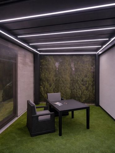 Outdoor dining area under motorized aluminum louvered pergola.