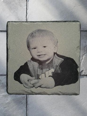 Engraved stone tile with a child's photo on a stone pavement.