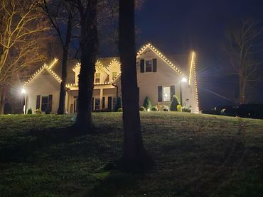House decorated with warm white string lights at night.