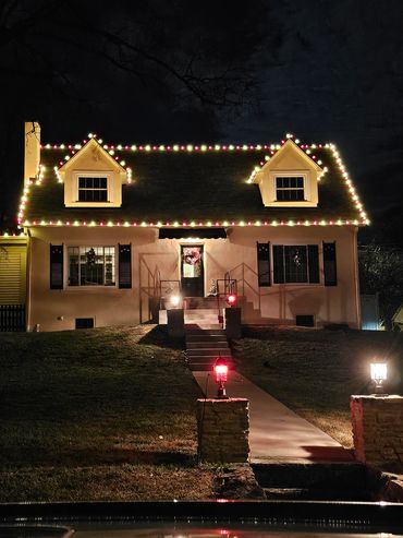 A cozy house decorated with Christmas lights at night.