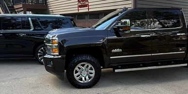 Two black Chevrolet vehicles parked side by side on a driveway.