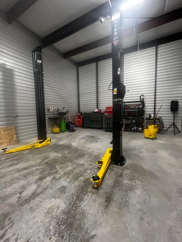Empty car lift inside a clean, organized garage with tools and equipment.