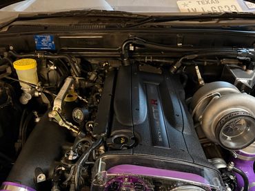 Engine bay of a Nissan Skyline GT-R with a large turbocharger and purple accents.