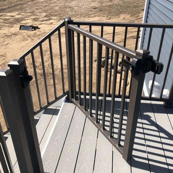 A metal safety gate installed on a deck with gray flooring.
