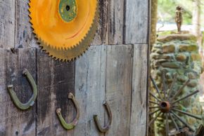 Rusty horseshoes and a circular saw blade on a wooden wall.