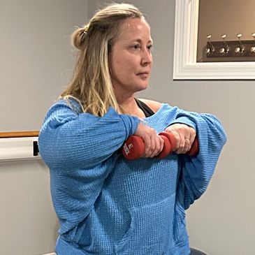 Woman exercising with dumbbells indoors.