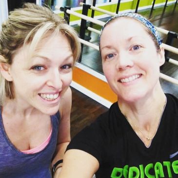 Two women smiling during a workout selfie.