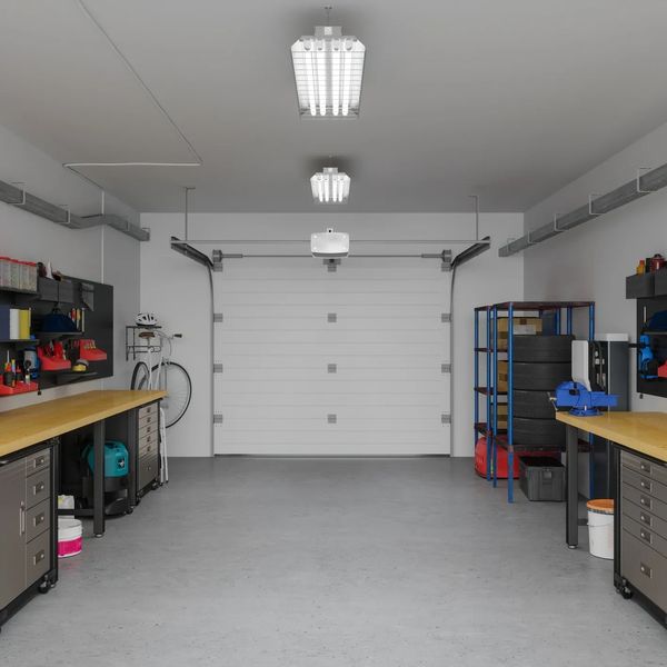 A clean, organized garage with workbenches and tools on both sides.