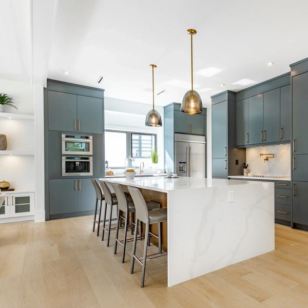 Modern kitchen with blue cabinets, white island, and pendant lights.