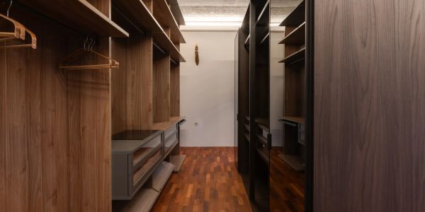 Modern walk-in closet with wooden shelves and hangers.