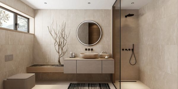 Modern beige bathroom with round mirror and glass shower enclosure.
