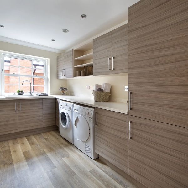 Modern laundry room with wood cabinets, washer, and dryer under a bright window.