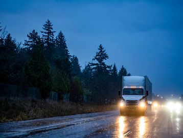 semi-truck driving at night in rain