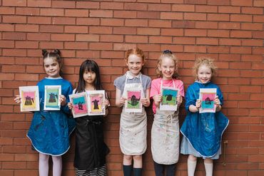 Children displaying their work with bright colours and teapot designs