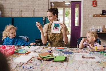 Art teacher showing children how to do block printing based on artist from Sheffield