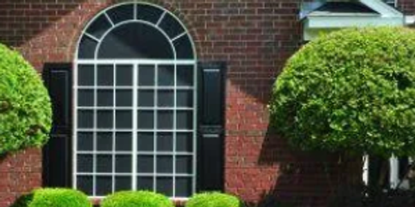 Arched solar screen window on a brick house. Solar screen with white, grid frame