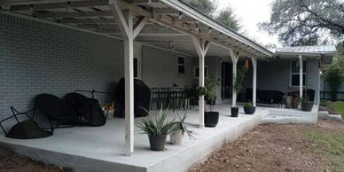 Outdoor patio with seating and potted plants under a covered porch.