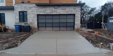 Freshly poured concrete driveway in front of a modern garage.
