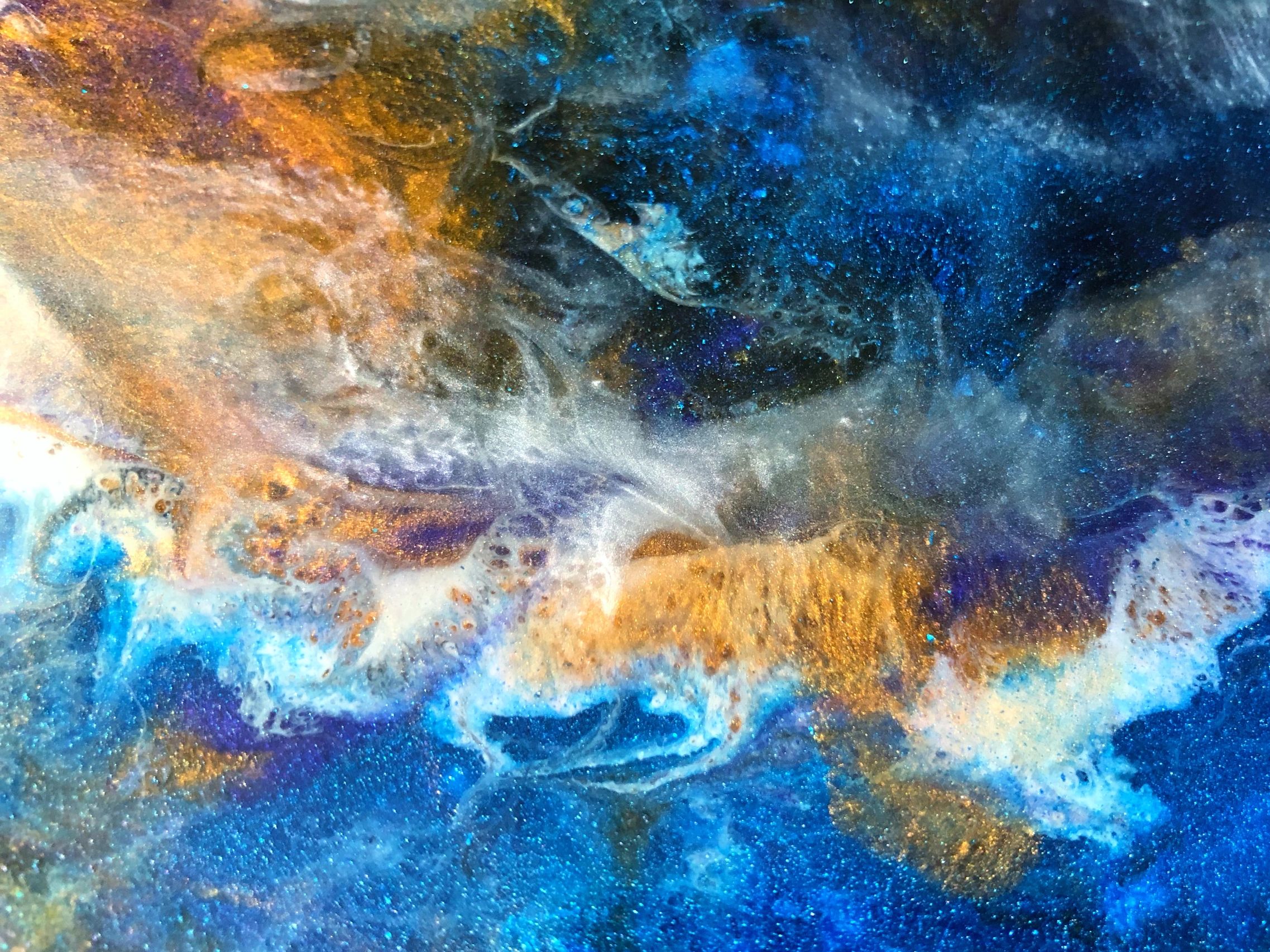 Abstract fluid art with vibrant blue, gold, and white swirls.