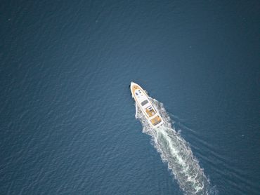 Aerial view of a yacht moving through deep blue water.
