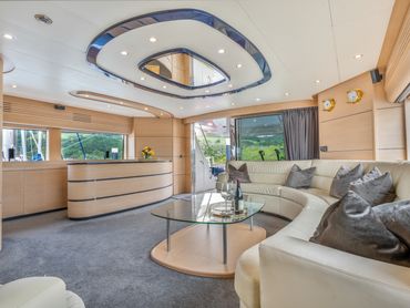 Luxurious yacht interior with curved cream sofa and glass coffee table.