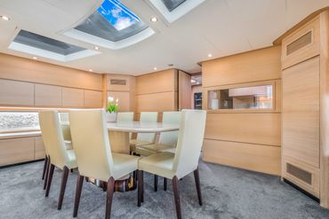 Modern dining area with cream chairs and skylights on a yacht.
