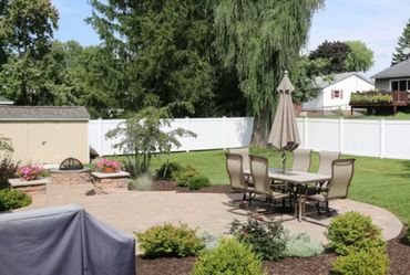 A backyard patio with outdoor dining furniture and greenery.