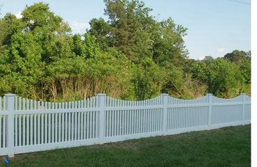 White vinyl privacy fence in a sunny field.