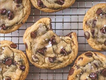 Chocolate chip cookies on a cooling rack, one bitten.