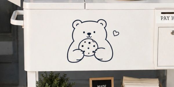 Cute bear holding a cookie illustration on a white freezer.