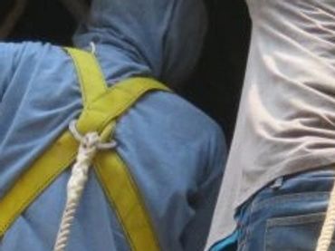 Technicians in protective coveralls installing an industrial exhaust fan through a rooftop opening