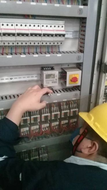 Technician inspecting the electrical control panel of an industrial exhaust fan system