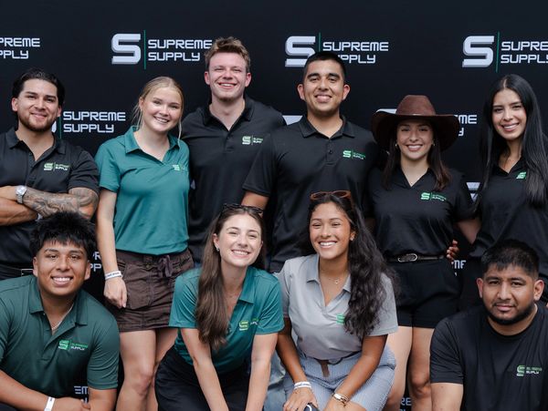 Group photo of smiling people in Supreme Supply attire.