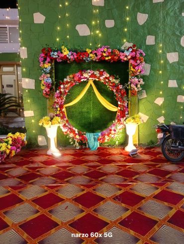 Decorative floral arch with lights on green wall.