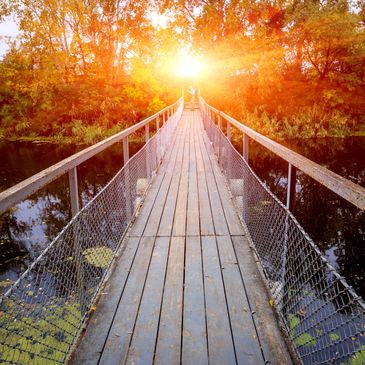 wooden bridge over river. sunrise in the background.
