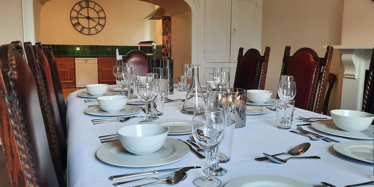 Elegant dining table set with white bowls, plates, and glassware in a cozy room.