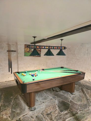 Further views of the pool table in play, upon stone flooring.