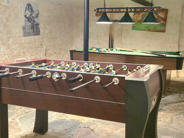 Front view of the football table and pool table in the background, canvas pictures on the wall.