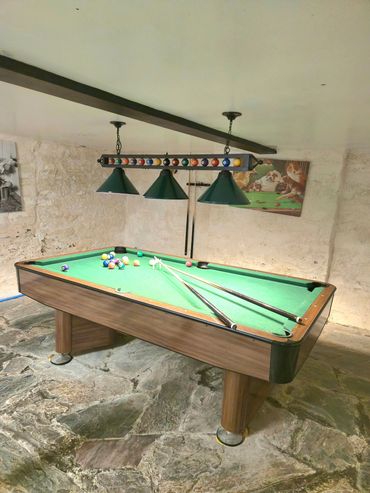 Action shot of pool table in full play with cue sticks at the ready and balls scattered around.