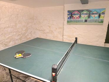 Close up view of the table tennis table with bats and balls, hung picture of colourful campervans.