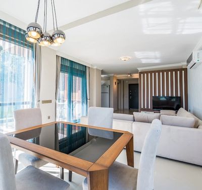 Bright modern living room with dining table and large windows.