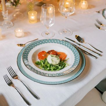 Elegant plated appetizer with smoked salmon and greens on fine china.