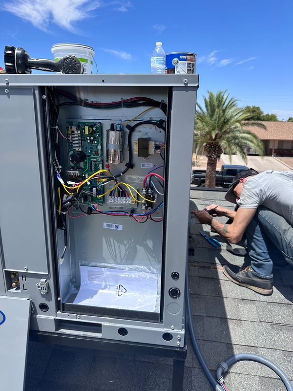 HVAC technician performing rooftop unit installation for residential air conditioning system.