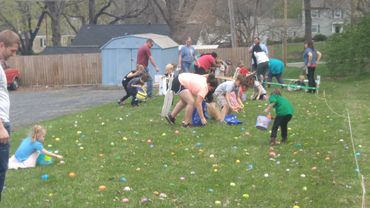 Children eagerly collecting colorful eggs during an outdoor Easter egg hunt on a grassy field.