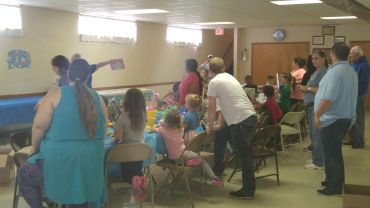 A group of children and adults gathered in a room for a party or event.